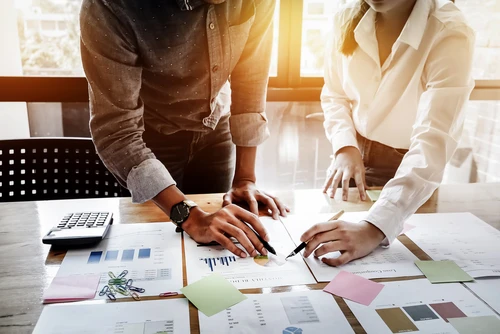Deux professionnels analysent des documents financiers sur une table de bureau