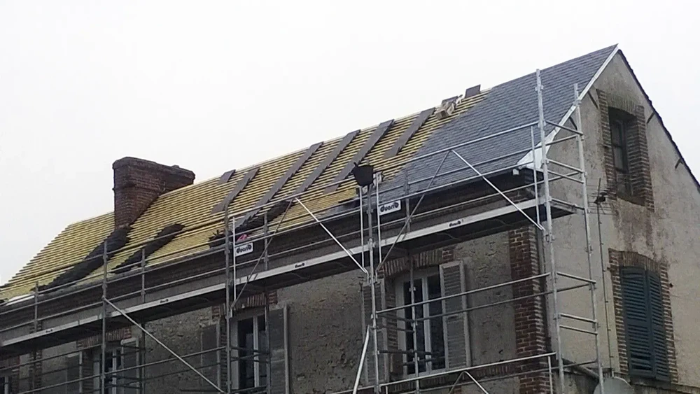 Chantier de rénovation extérieure d'une maison ancienne en briques avec échafaudage métallique