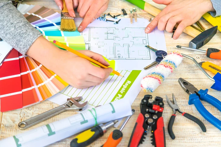 Mains humaines travaillant sur plans d'architecture avec nuanciers de couleurs sur table en bois