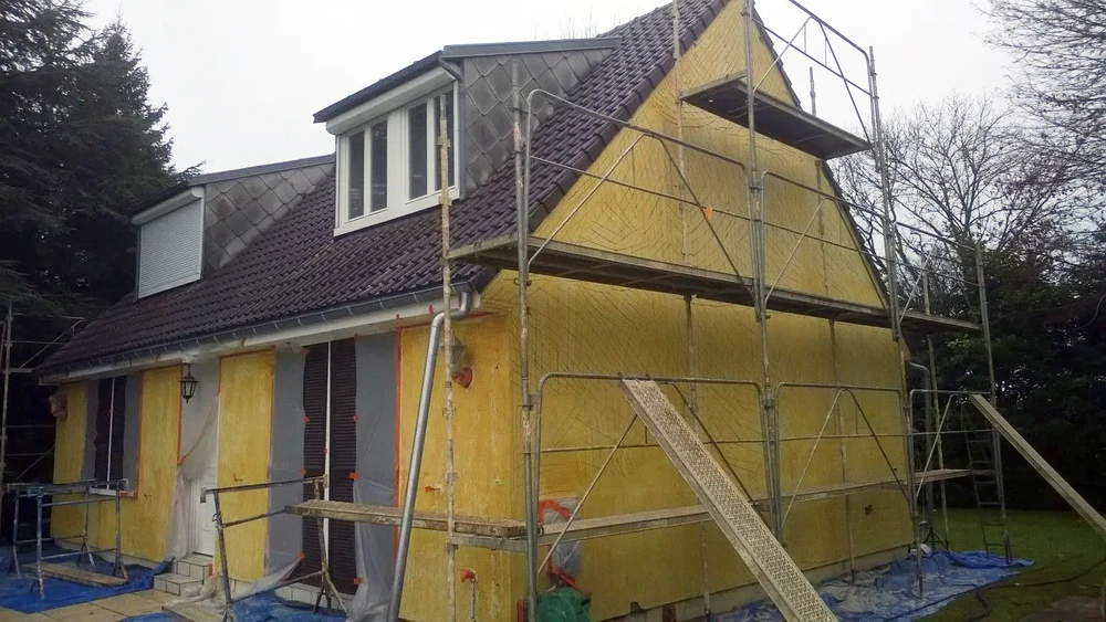 Chantier de rénovation extérieure d'une maison individuelle avec échafaudage métallique installé