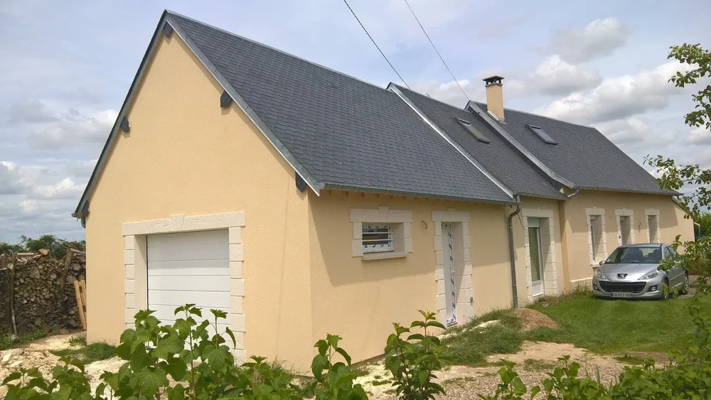 Maison individuelle contemporaine avec garage attenant, façade enduite beige, encadrements pierre claire