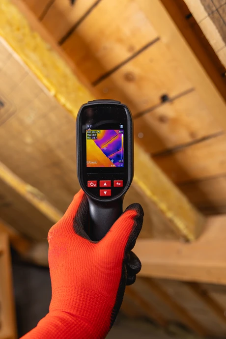 Chantier d'isolation thermique sous toiture avec pose d'isolant en laine minérale jaune entre chevrons métalliques
